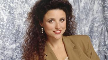 Portrait of woman with large curly brown hair in taupe power blazer.